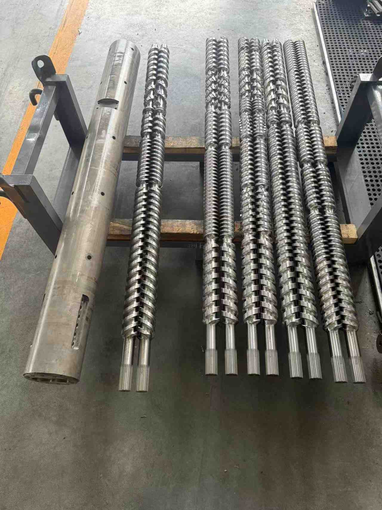 Twin-screw extruder screw and matching barrel, with the barrel on the left and multiple sets of twin screws on the right